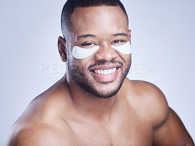 Buy stock photo Studio shot of a handsome young man wearing an under eye patch against a blue background