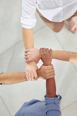 Buy stock photo High angle shot of a group of unrecognizable businesspeople holding on to each other's arms at work