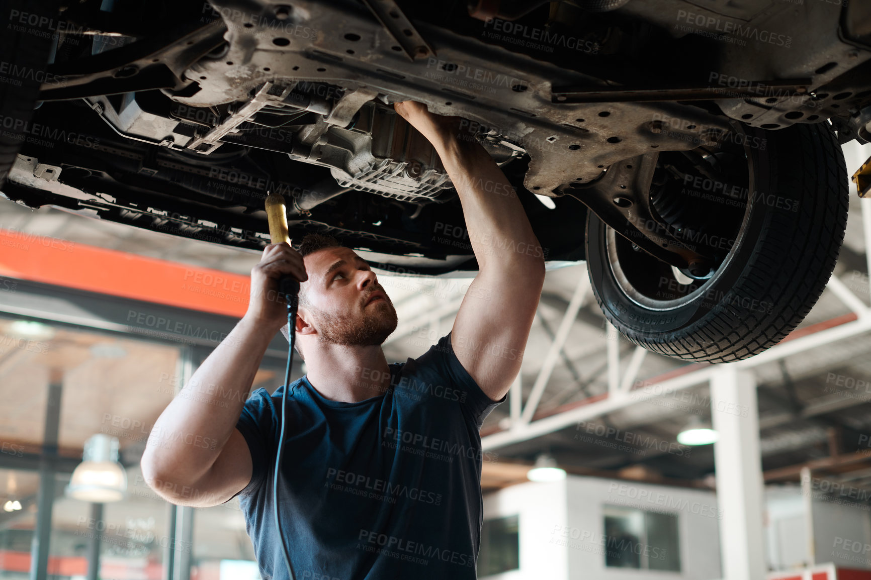 Buy stock photo Torch, inspection and mechanic with car in garage for service, maintenance or repair for safety. Light, auto engineering and male industrial worker checking bottom of vehicle for oil leak in workshop