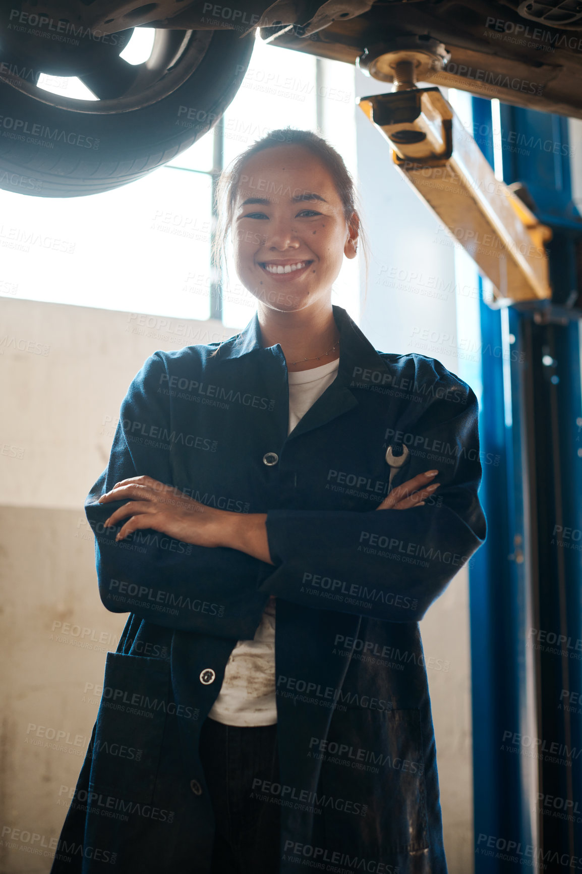 Buy stock photo Shot of a female mechanic posing with her arms crossed in an auto repair shop