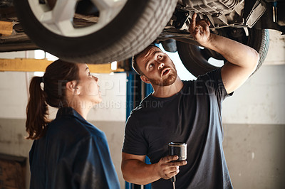 Buy stock photo Shot of two mechanics working under a car in an auto repair shop