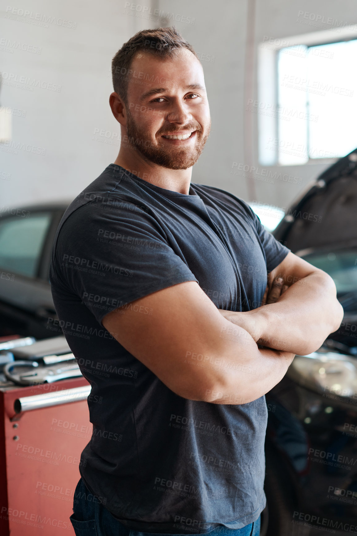 Buy stock photo Shot of a mechanic posing with his arms crossed in an auto repair shop