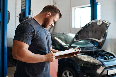 Buy stock photo Shot of a mechanic holding a clipboard while working in an auto repair shop