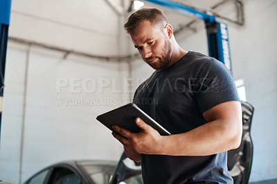 Buy stock photo Shot of a mechanic using a digital tablet while working in an auto repair shop