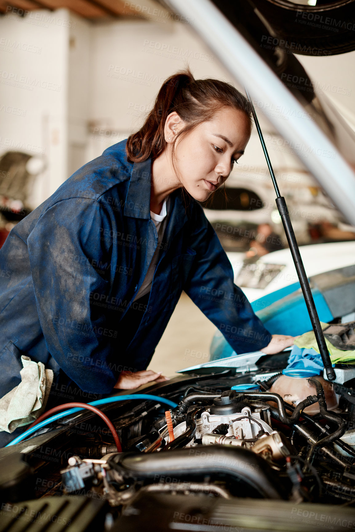 Buy stock photo Shot of a female mechanic working on a car in an auto repair shop