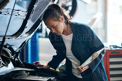 Buy stock photo Shot of a female mechanic working on a car in an auto repair shop