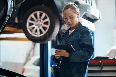 Buy stock photo Shot of a female mechanic holding a digital tablet while working in an auto repair shop