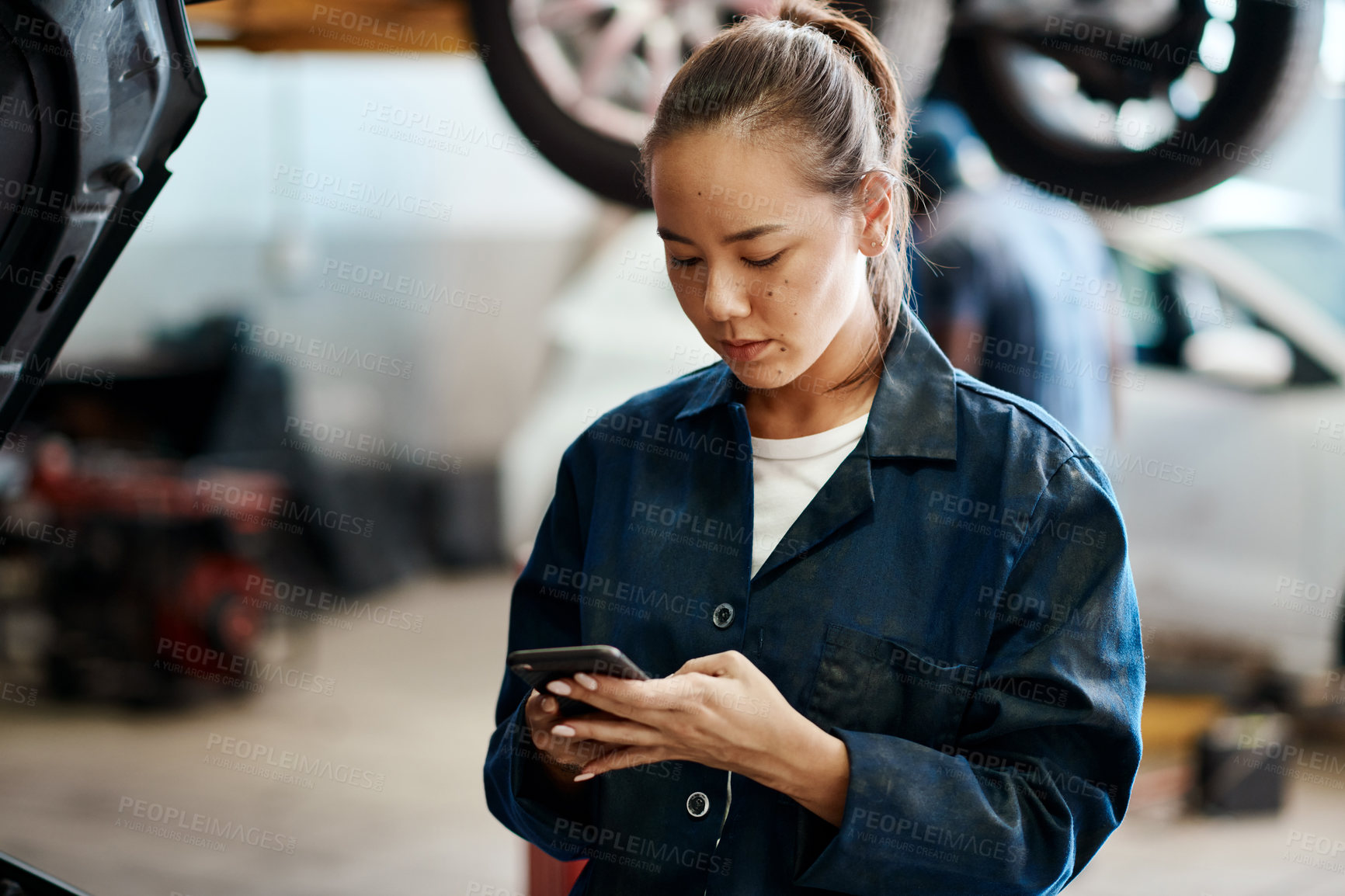 Buy stock photo Woman, smartphone and repairs in garage for internet, research and car service in workshop. Female mechanic, reading and technology with information for ideas, maintenance and quality assurance