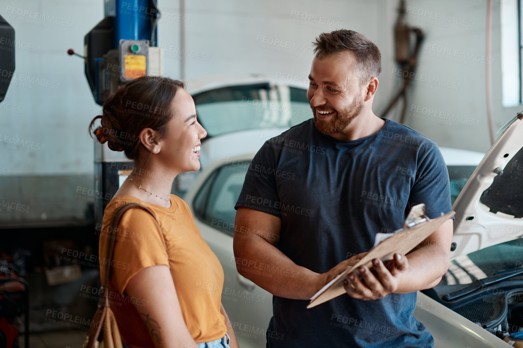 Buy stock photo Shot of a woman talking to a mechanic in an auto repair shop