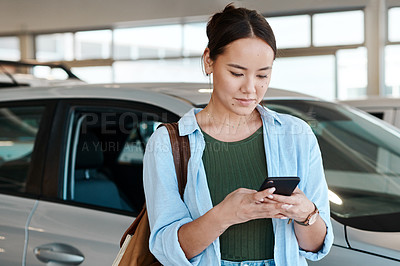 Buy stock photo Asian woman, typing and phone at car dealership to sale, customer and website for research. Female person, communication and mobile app for vehicle review or online survey, showroom and social media