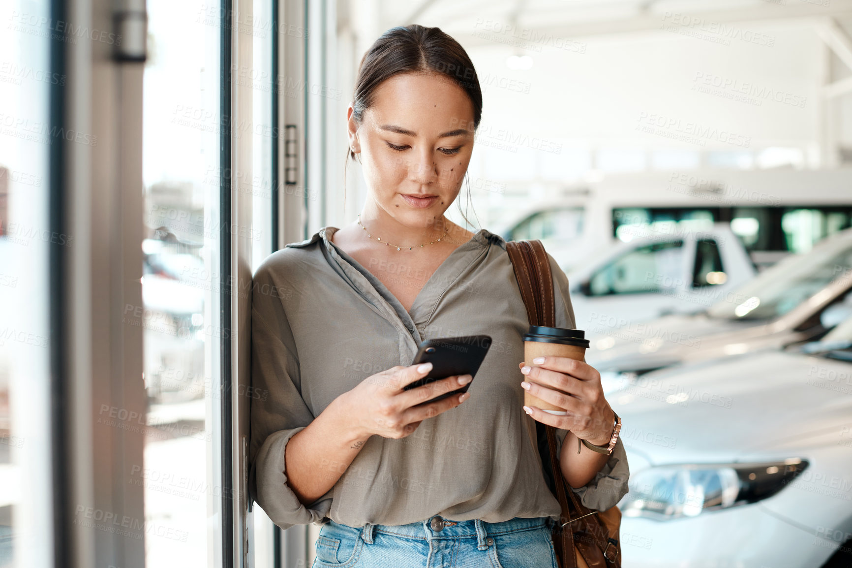 Buy stock photo Cellphone, coffee and female person in a showroom typing a text message or scrolling on social media. Communication, technology and woman browsing on a mobile app with a cellphone at a car dealership
