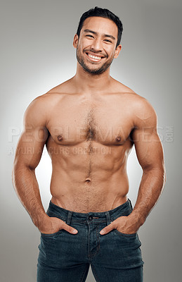 Buy stock photo Shot of a handsome young man standing alone and posing shirtless in the studio