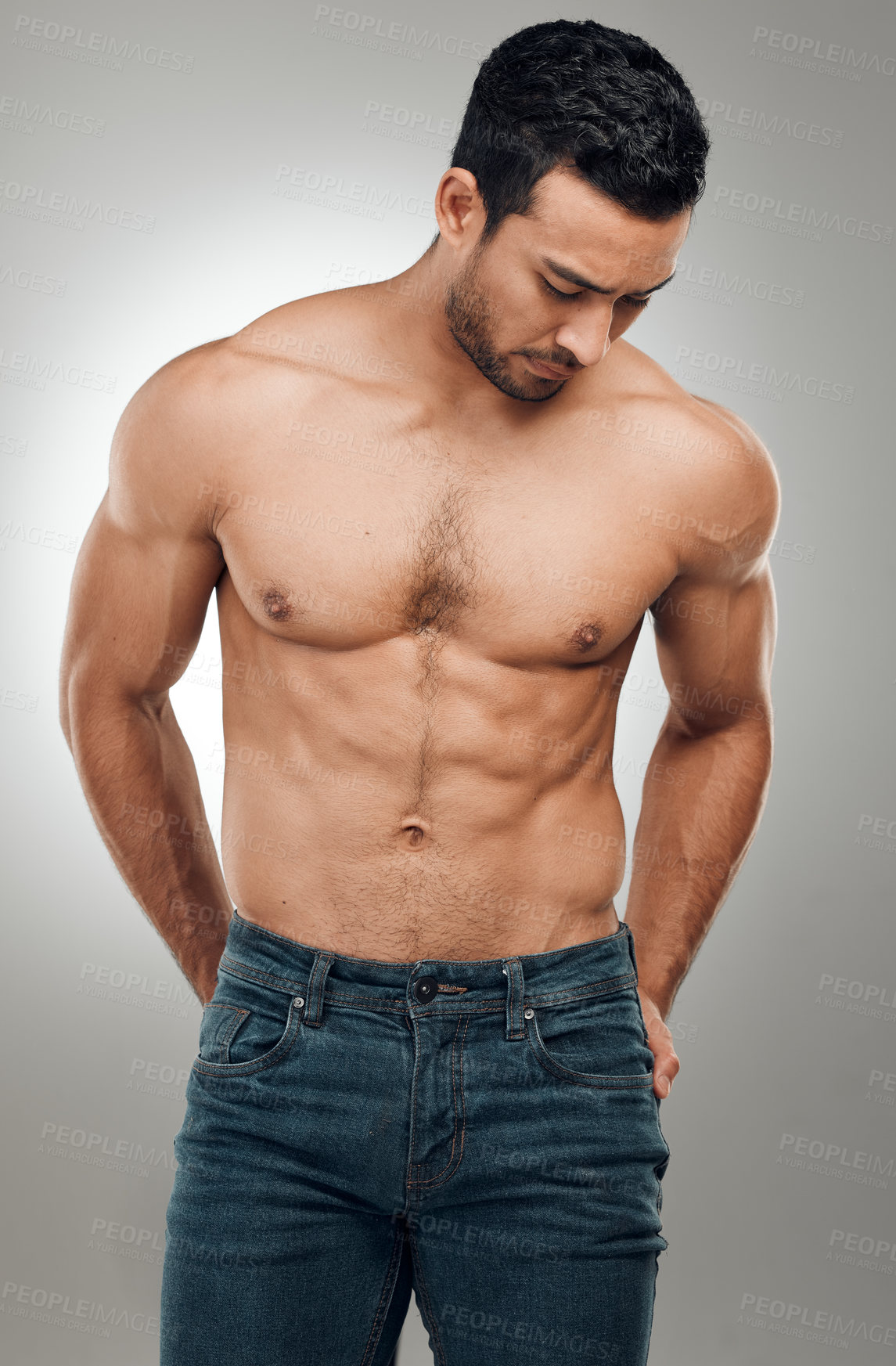 Buy stock photo Shot of a handsome young man standing alone and posing shirtless in the studio