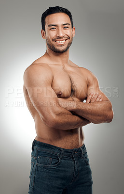 Buy stock photo Shot of a handsome young man standing alone in the studio posing shirtless with his arms folded