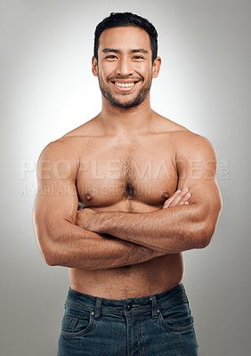 Buy stock photo Shot of a handsome young man standing alone in the studio posing shirtless with his arms folded