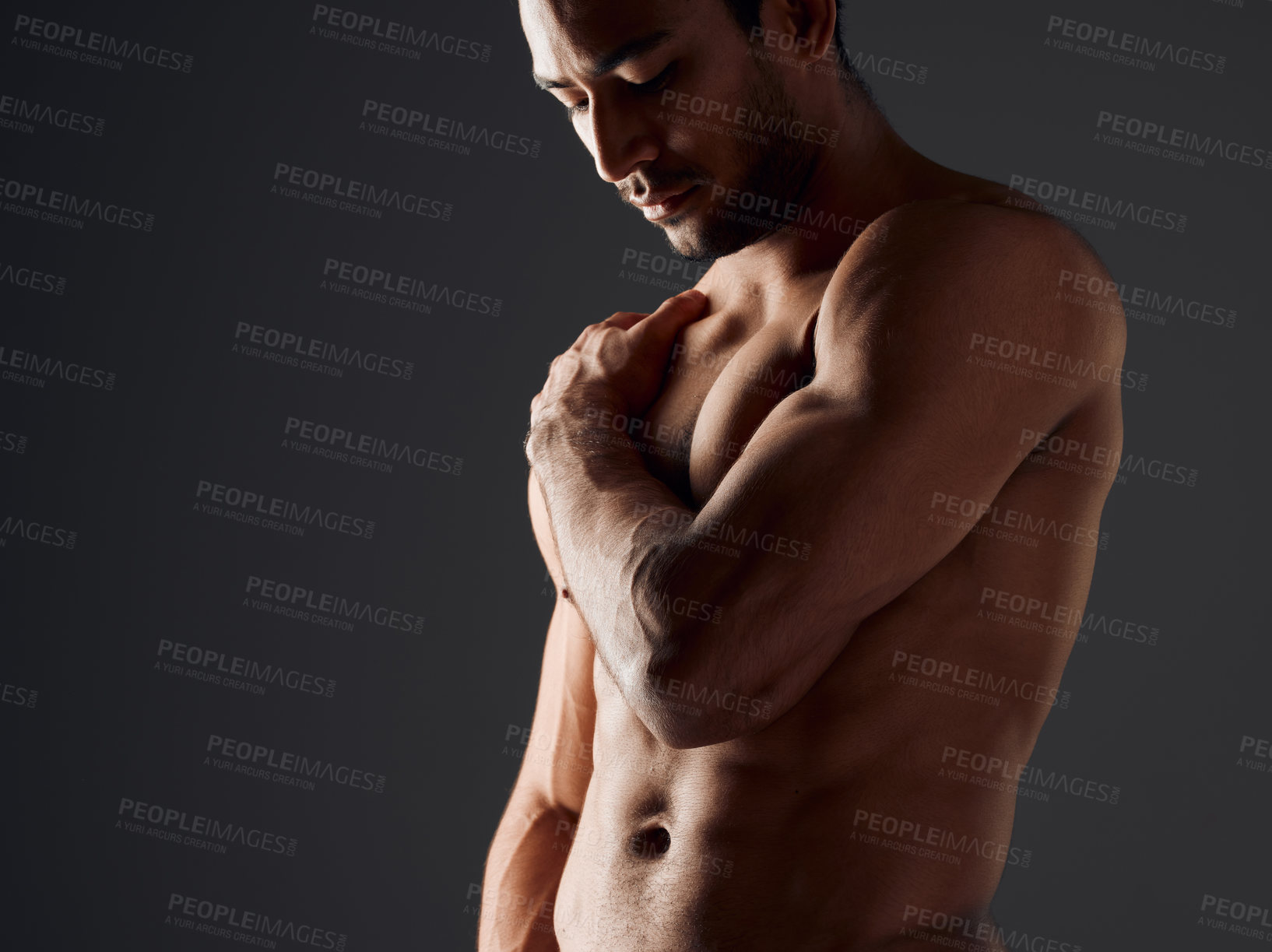 Buy stock photo Shot of a handsome young man standing alone and posing shirtless in the studio