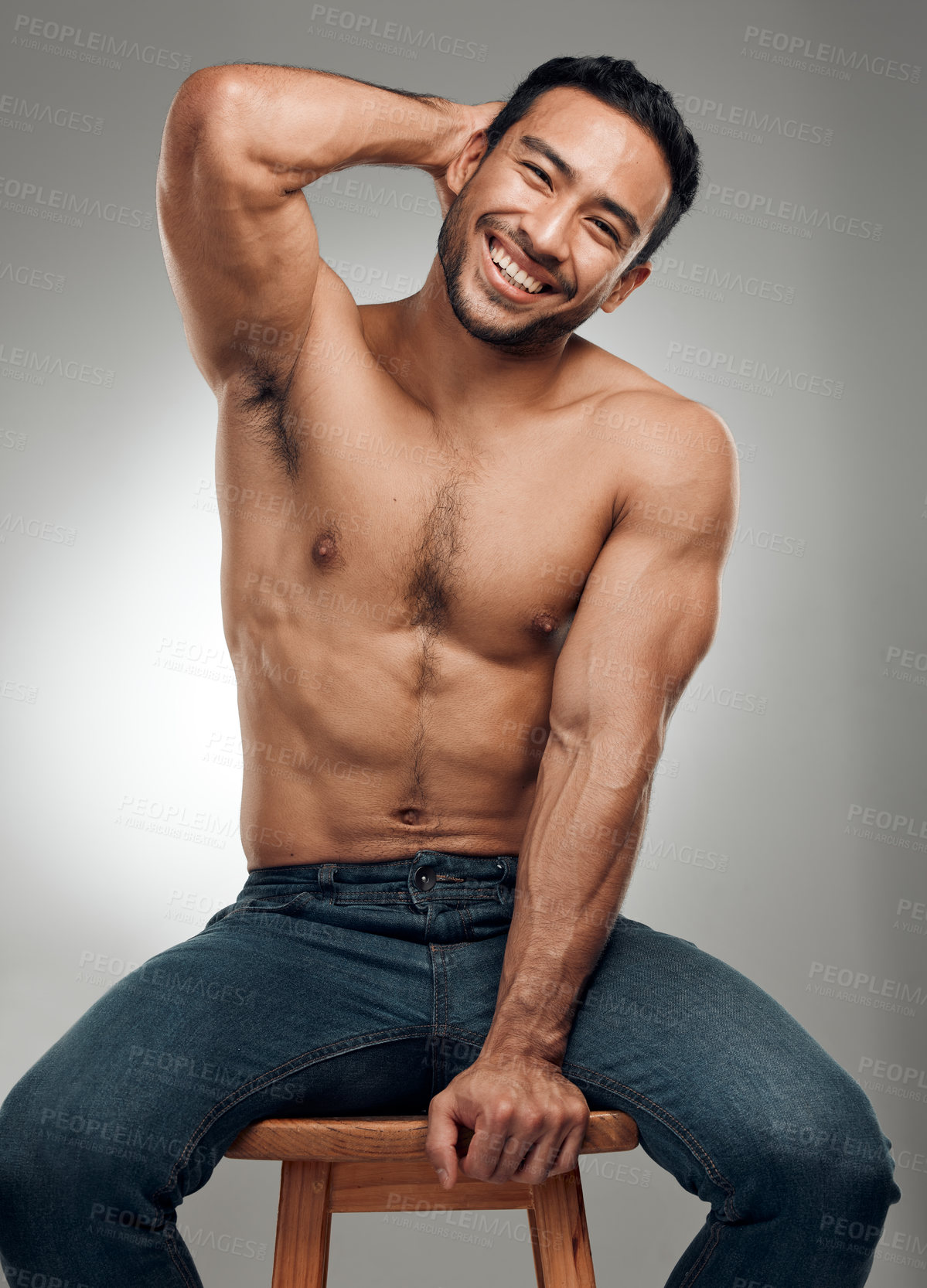 Buy stock photo Shot of a handsome young man sitting on a stool in the studio and posing shirtless