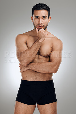 Buy stock photo Shot of a handsome young man standing alone and posing shirtless in the studio