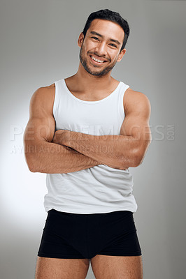 Buy stock photo Shot of a handsome young man standing alone in the studio with his arms folded