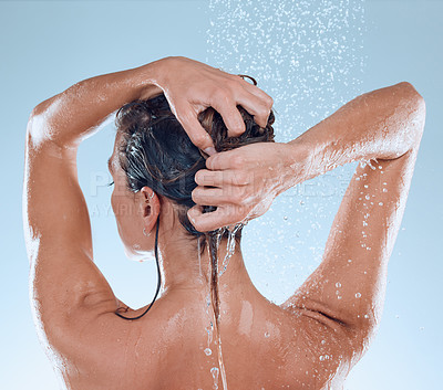 Buy stock photo Studio shot of a young woman taking a shower against a blue background