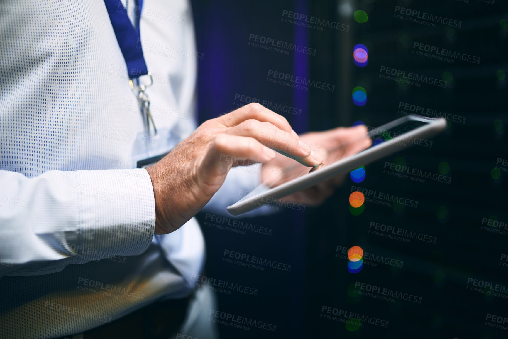 Buy stock photo Closeup shot of an unrecognisable man using a digital tablet while working in a server room