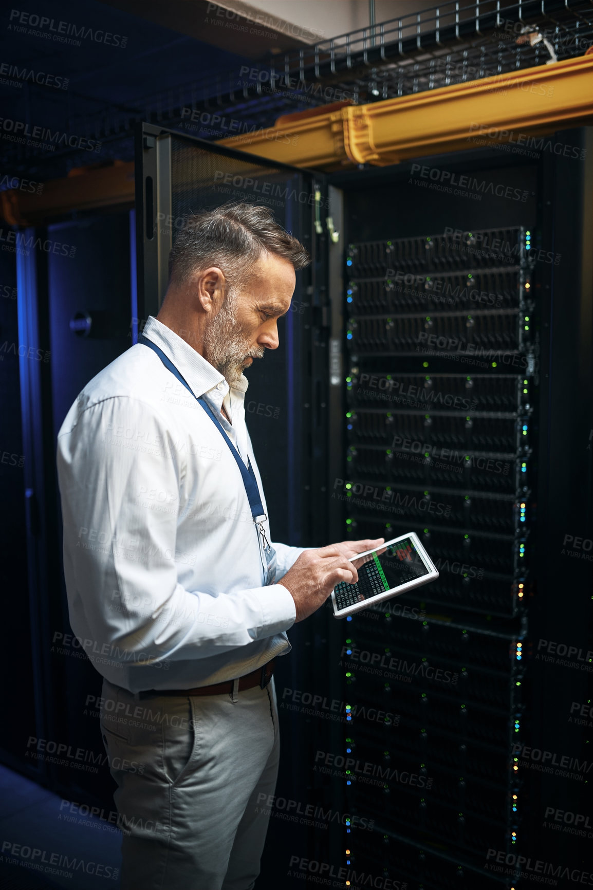 Buy stock photo Shot of a mature man using a digital tablet while working in a server room