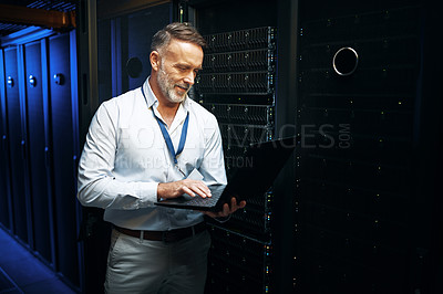 Buy stock photo Shot of a mature man using a laptop while working in a server room