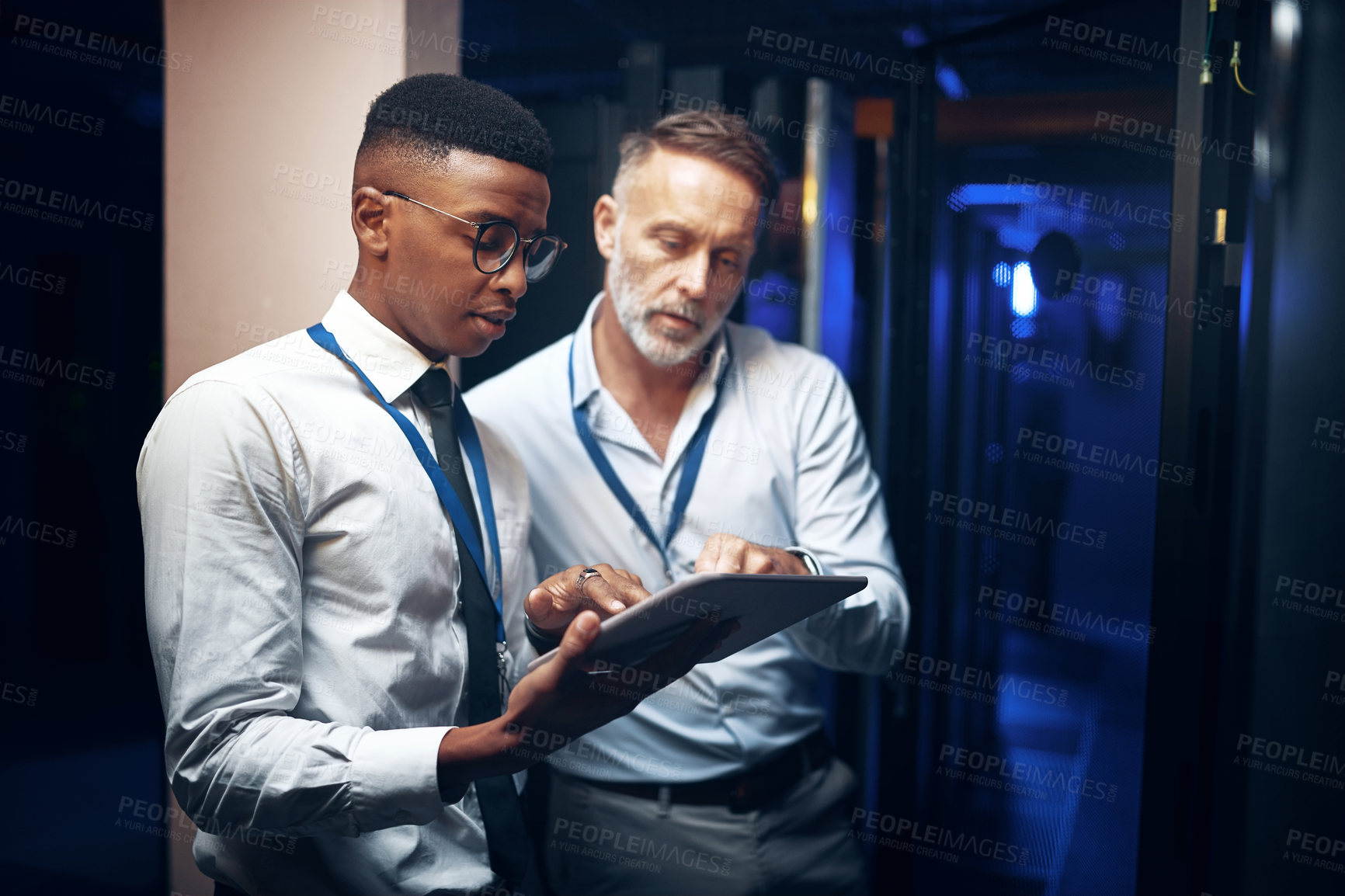 Buy stock photo Shot of two technicians using a digital tablet while working in a server room