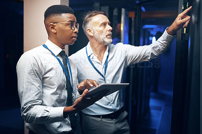 Buy stock photo Shot of two technicians using a digital tablet while working in a server room