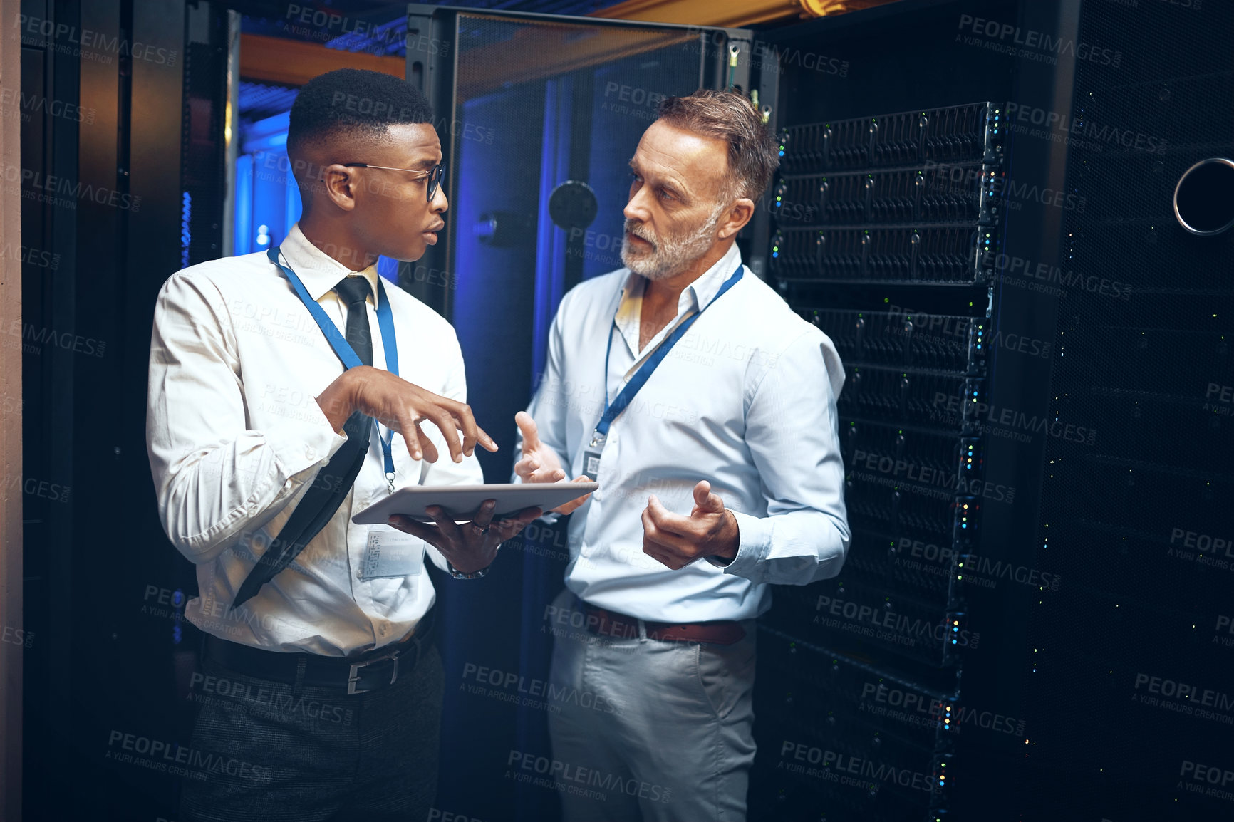 Buy stock photo Shot of two technicians using a digital tablet while working in a server room