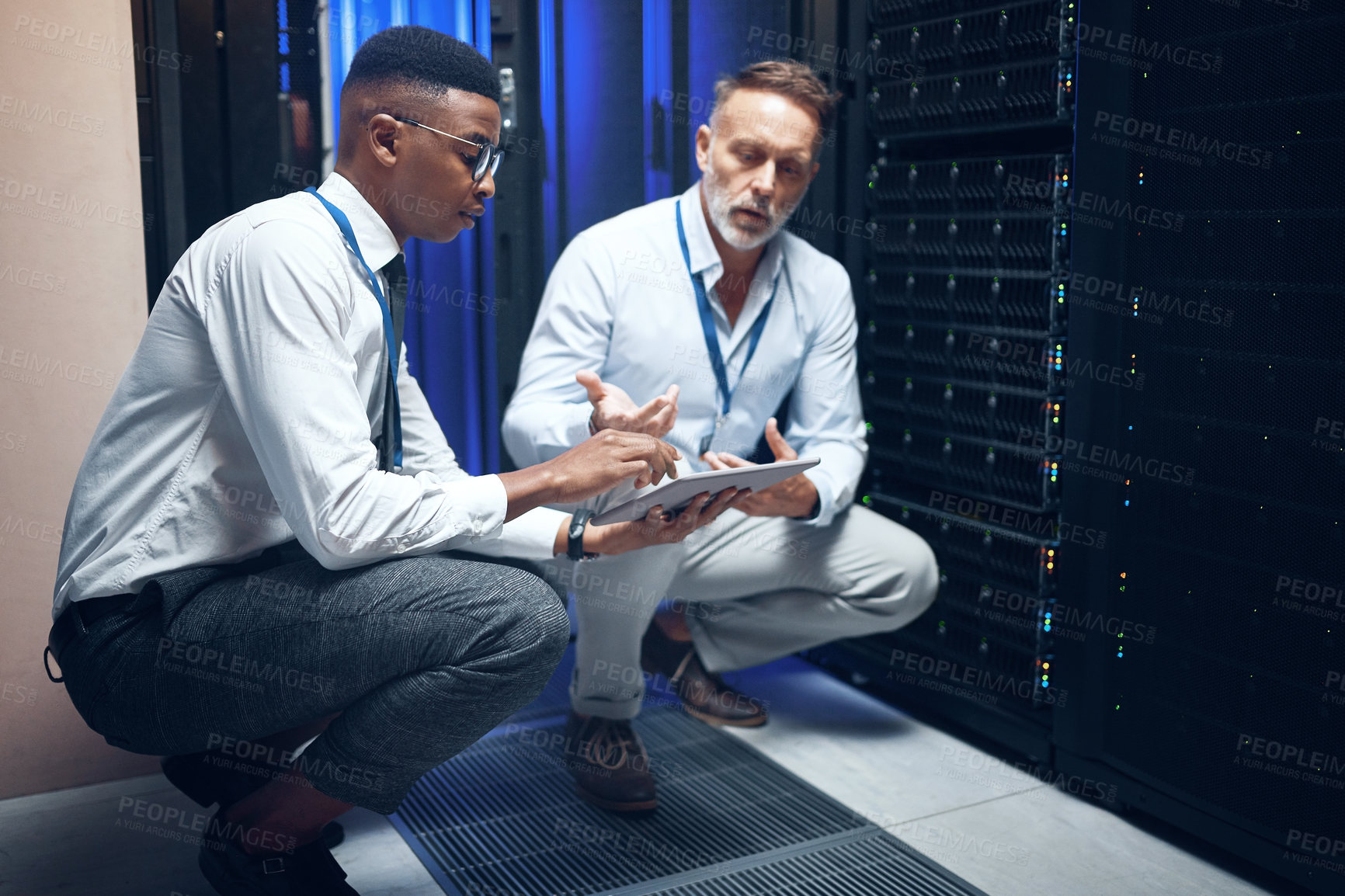 Buy stock photo Shot of two technicians using a digital tablet while working in a server room