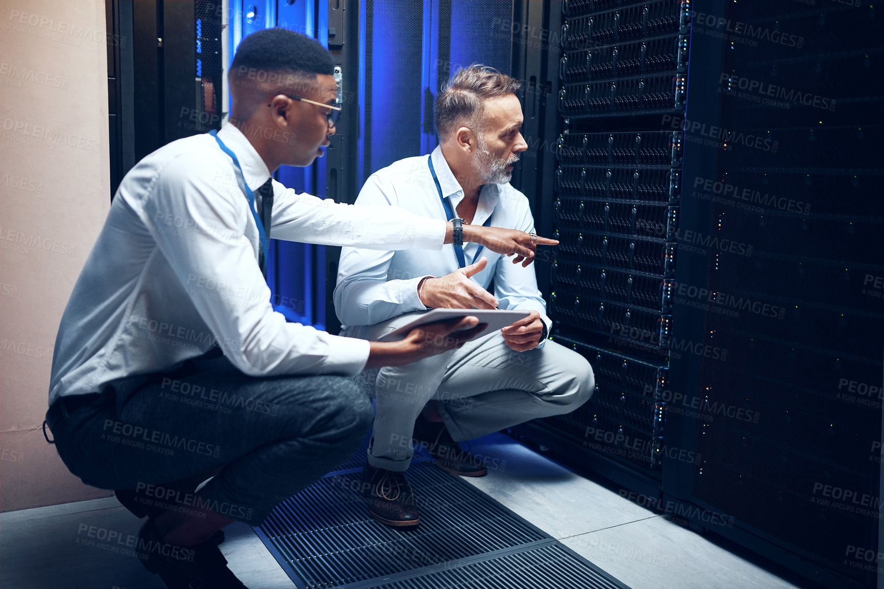 Buy stock photo Shot of two technicians using a digital tablet while working in a server room