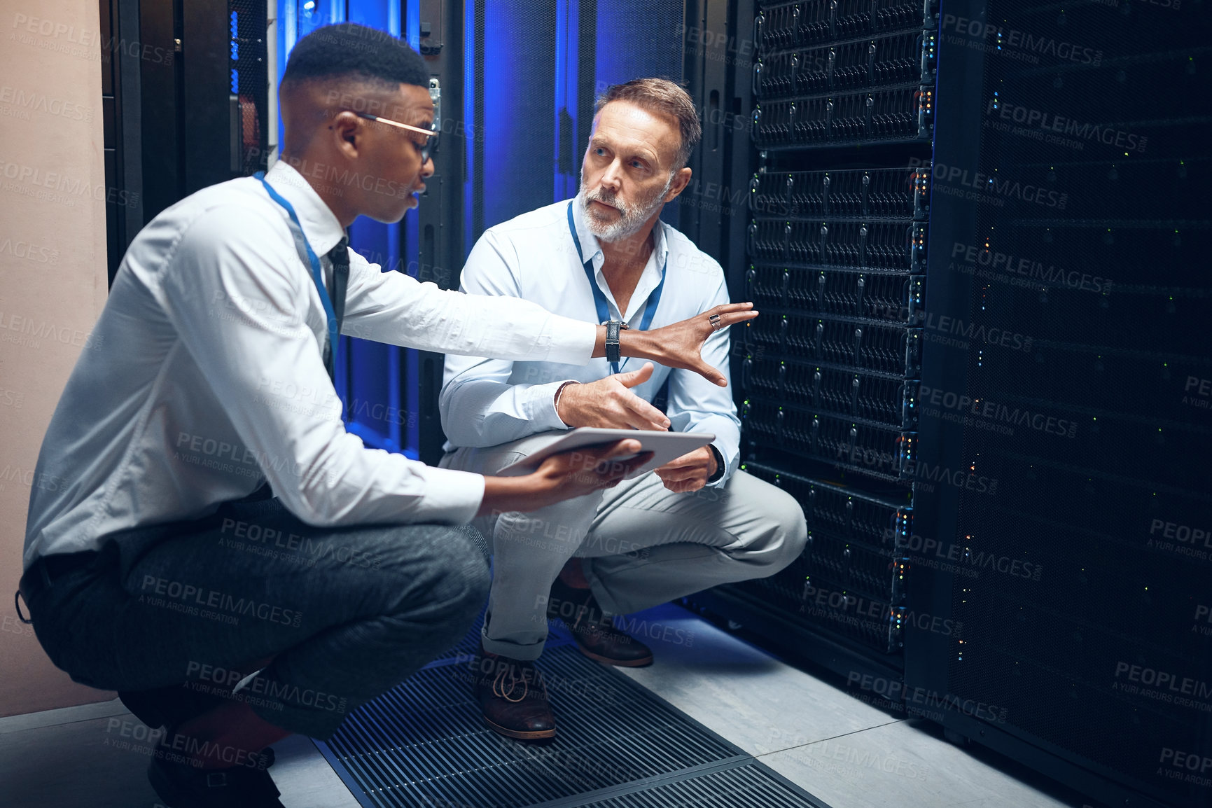 Buy stock photo Shot of two technicians using a digital tablet while working in a server room