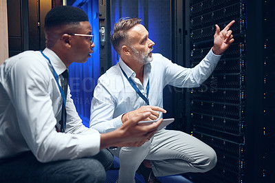 Buy stock photo Shot of two technicians using a digital tablet while working in a server room