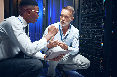 Buy stock photo Shot of two technicians using a digital tablet while working in a server room