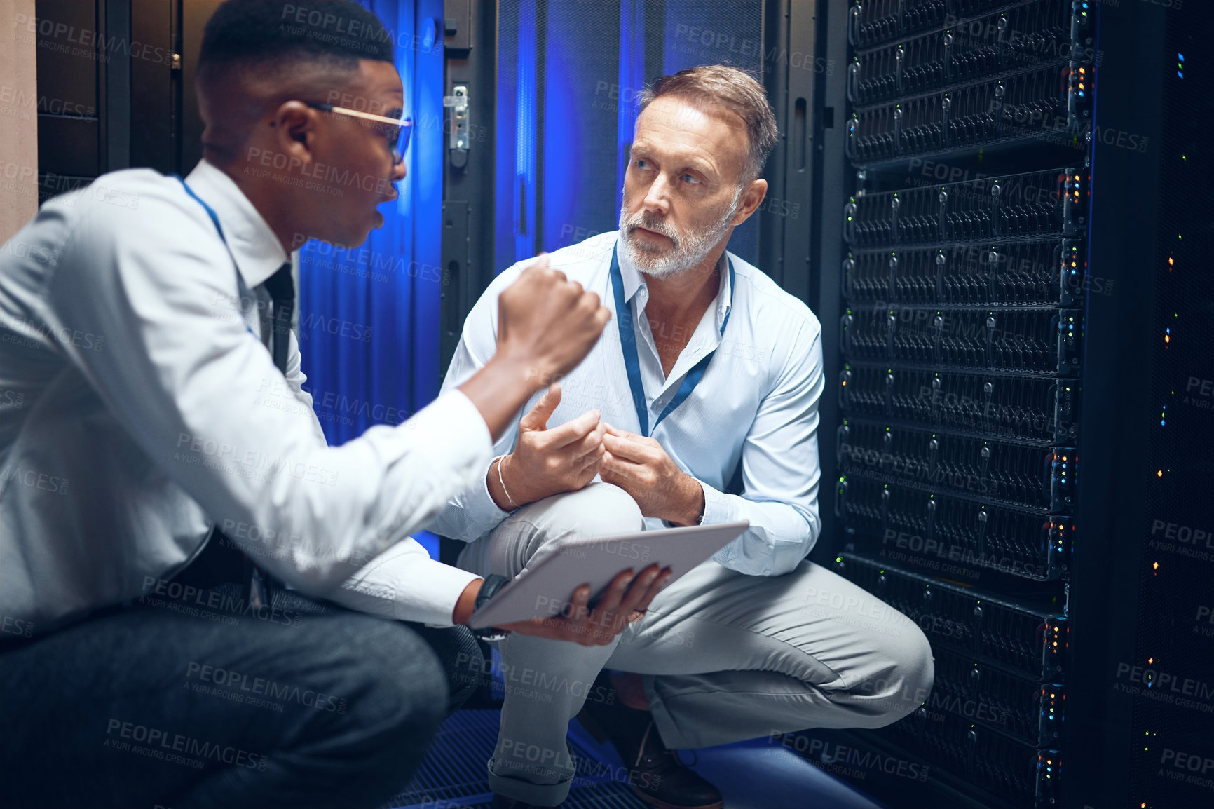 Buy stock photo Shot of two technicians using a digital tablet while working in a server room