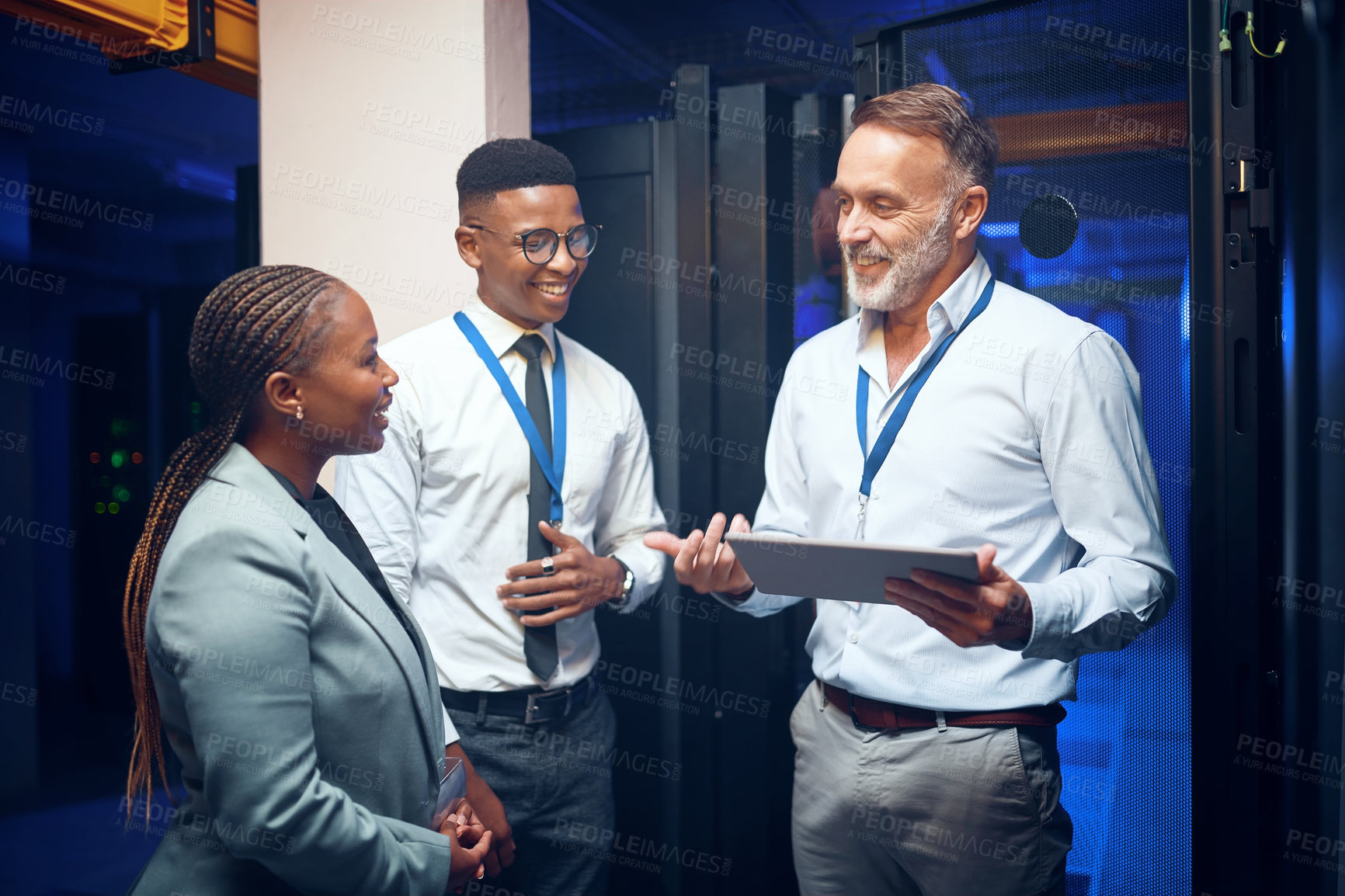 Buy stock photo Shot of a group of technicians using a digital tablet while working together in a server room