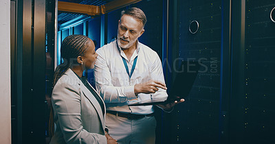 Buy stock photo Shot of two technicians using a laptop while working in a server room