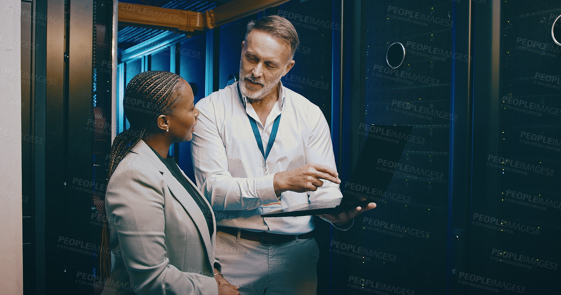 Buy stock photo Shot of two technicians using a laptop while working in a server room