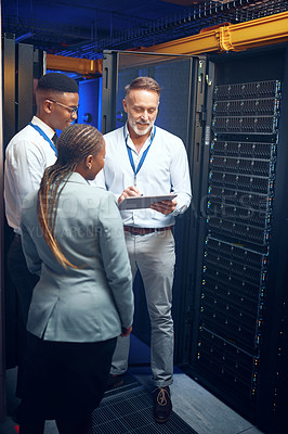 Buy stock photo Shot of a group of technicians using a digital tablet while working together in a server room