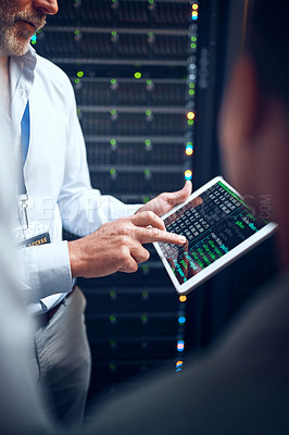 Buy stock photo Closeup shot of an unrecognisable man using a digital tablet while working with a colleague in a server room