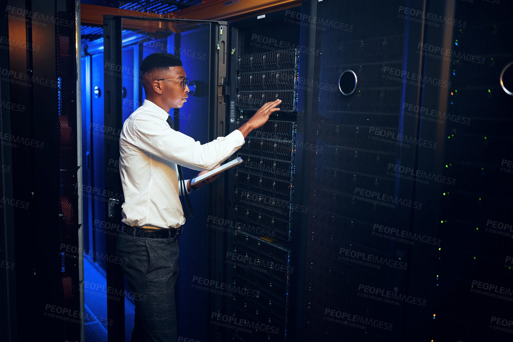 Buy stock photo Shot of a young man using a digital tablet while working in a server room