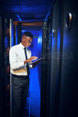 Buy stock photo Shot of a young man using a digital tablet while working in a server room