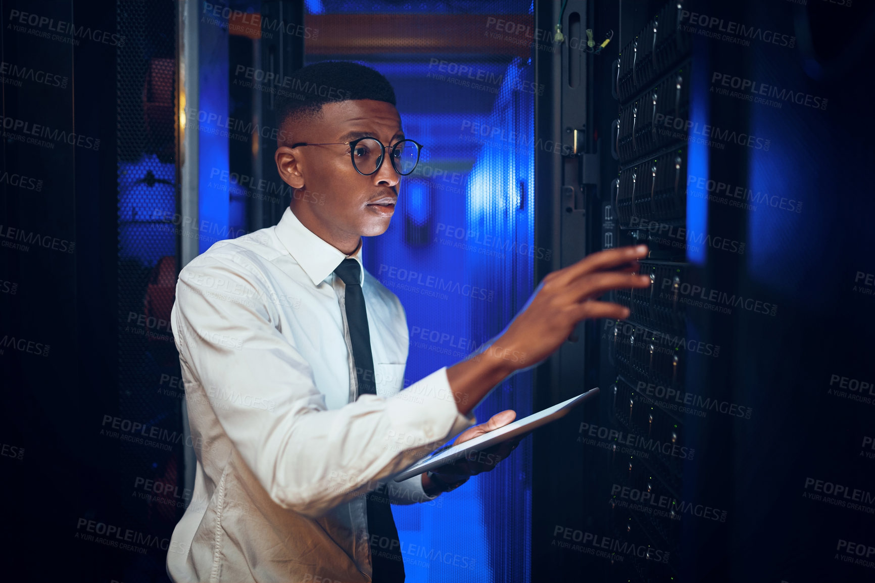 Buy stock photo Shot of a young man using a digital tablet while working in a server room