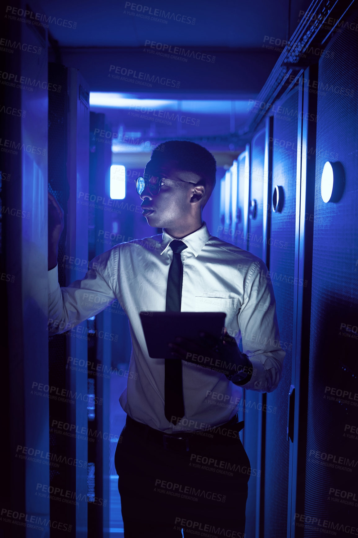 Buy stock photo Shot of a young man using a digital tablet while working in a server room