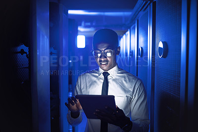 Buy stock photo Shot of a young man using a digital tablet while working in a server room