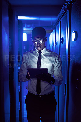 Buy stock photo Shot of a young man using a digital tablet while working in a server room