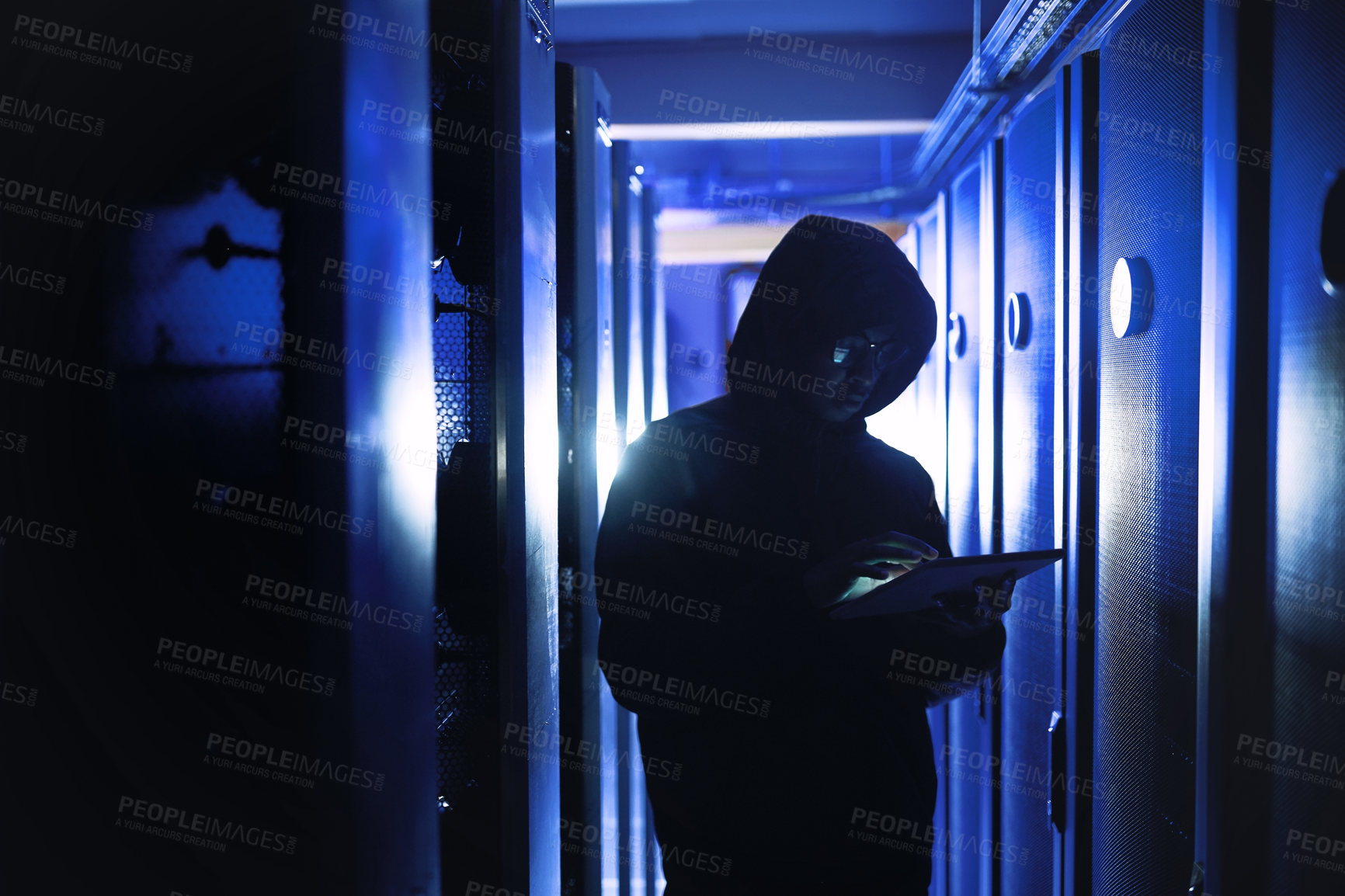 Buy stock photo Shot of a hacker using a digital tablet in a server room