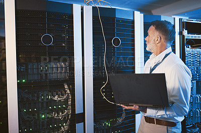 Buy stock photo Shot of a mature man using a laptop while working in a server room