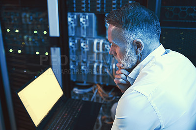 Buy stock photo High angle shot of a mature man looking thoughtful while using a laptop in a server room
